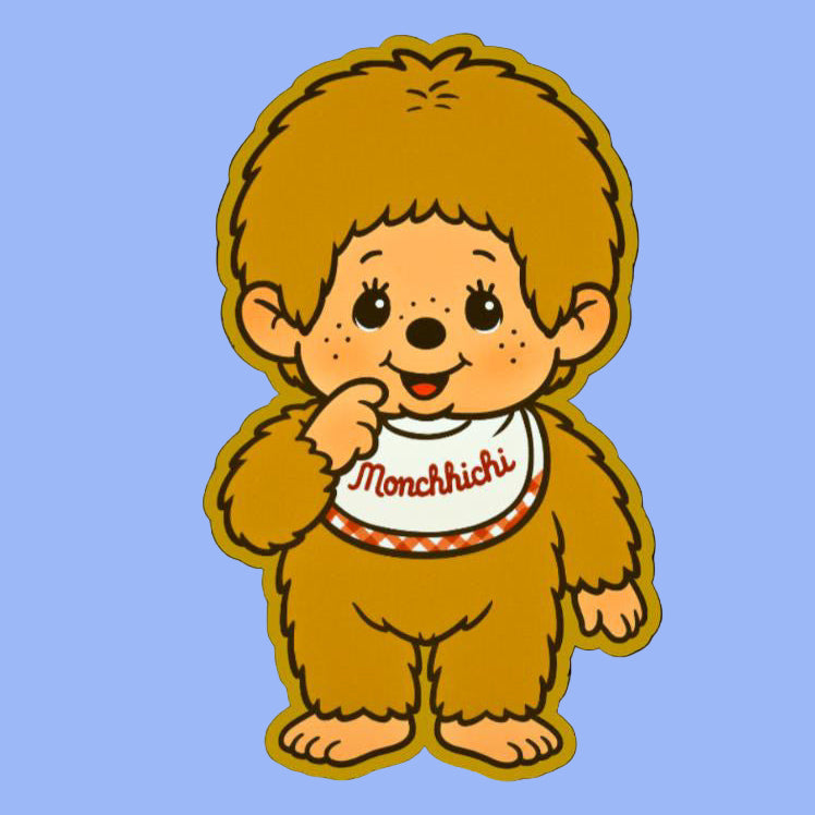 Biege Monchhichi character in a brown outfit with a white bib on a black background