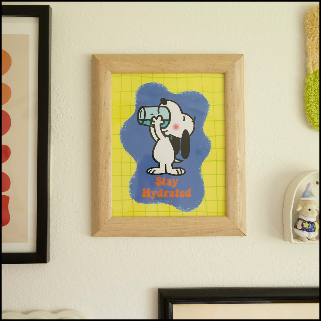 Framed artwork of a cartoon dog with a blue background on a wall with other framed pictures.
